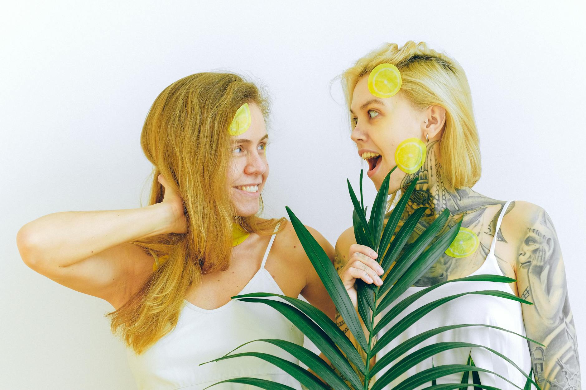 Two women smiling and expressing joy together indoors with tropical plants