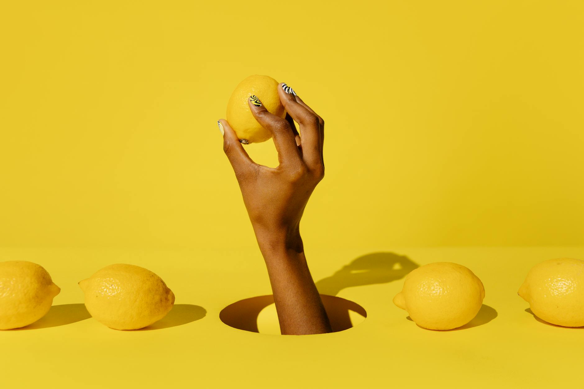A hand holding a fresh lemon against a vivid yellow background, symbolizing the refreshed approach to pleasure after 40