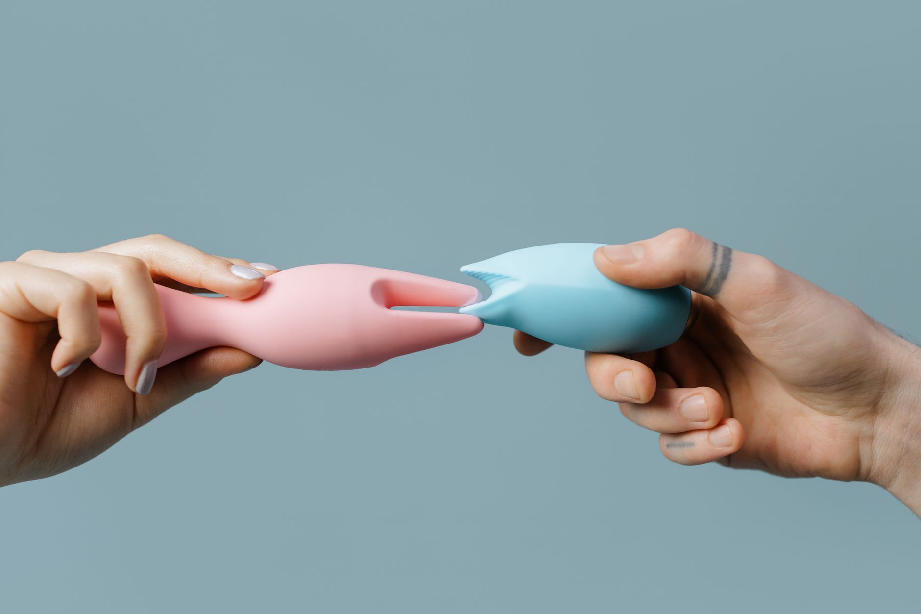 A blue silicone vibrator held in hand against a purple background