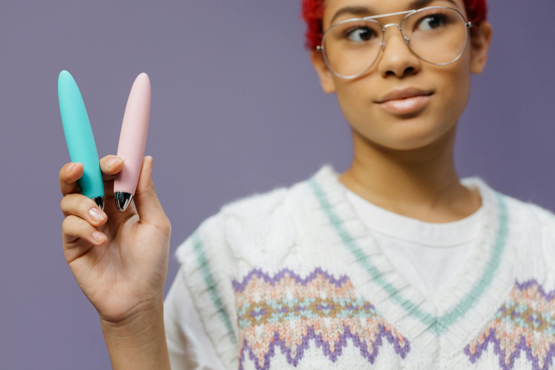Close-up of hands holding a blue personal massager against a knitted sweater, showing intimate support for pelvic wellness.