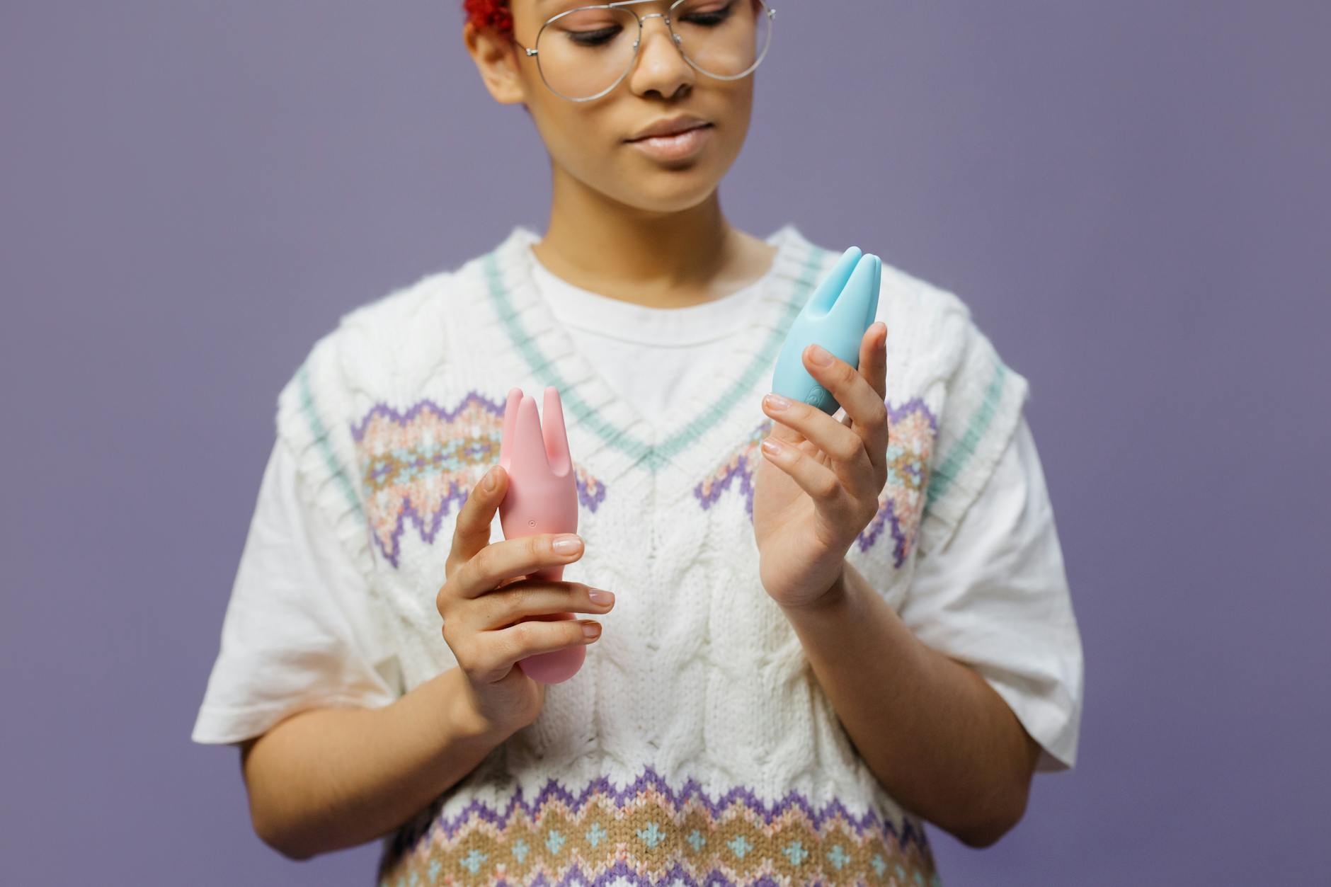 Woman holding a blue silicone clitoral vibrator in a contemplative moment