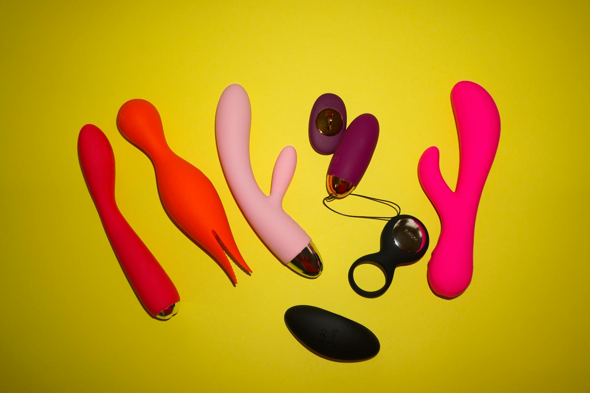 Femme portant des lunettes tenant deux vibromasseurs clitoridiens de couleurs différentes